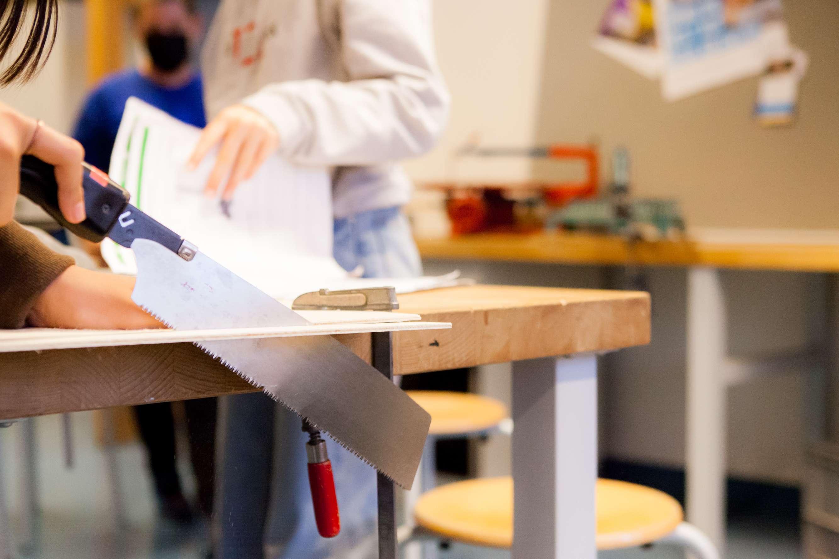 Schülerin sägt an einem Holzbrett