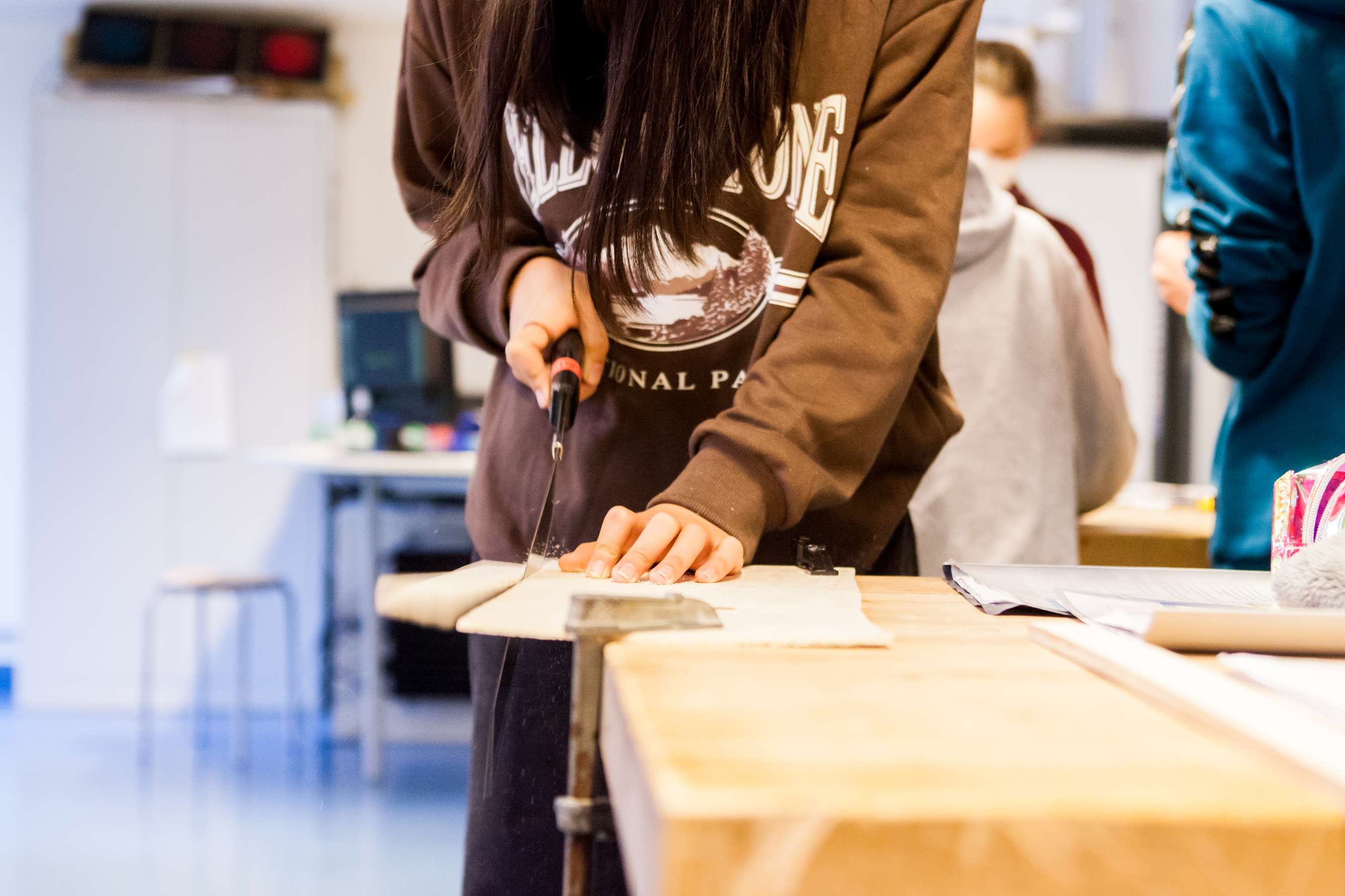 Schülerin sägt an einem Holzbrett