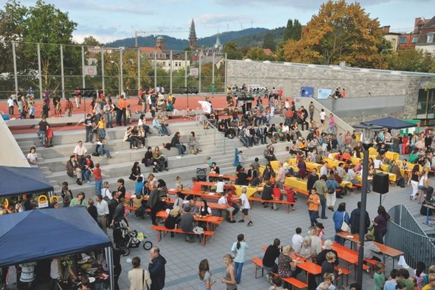 Schülerinnen, Schüler, Eltern und Lehrkräfte feiern auf dem Schulhof ein Fest