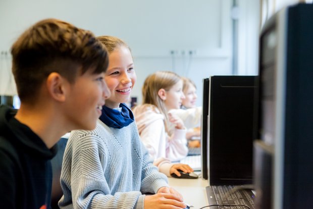 SchülerInnen arbeiten zusammen vor dem PC