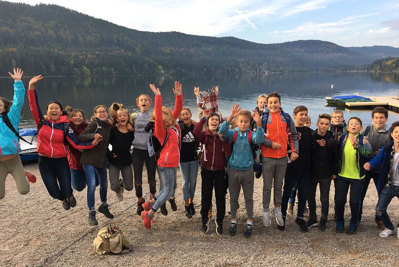 Schülerinnen und Schüler auf einer Klassenfahrt springen in die Luft.