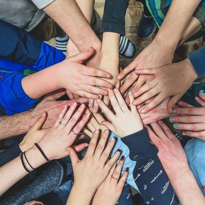 Schülerinnen und Schüler legen ihre Hände aufeinander