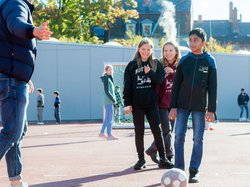 Ältere und jüngere Schülerinnen und Schüler spielen gemeinsam Fußball