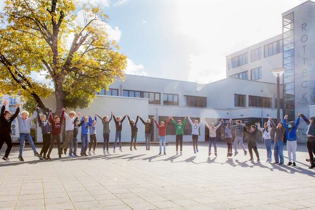 Schülerinnen und Schüler halten sich an den Händen und springen in die Höhe